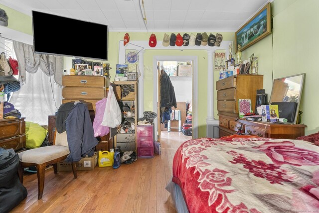 bedroom featuring crown molding, decorative columns, and light wood-type flooring