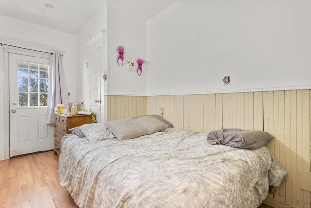 bedroom with wooden walls and light hardwood / wood-style floors