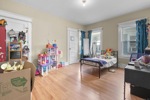 bedroom with cooling unit and light hardwood / wood-style flooring