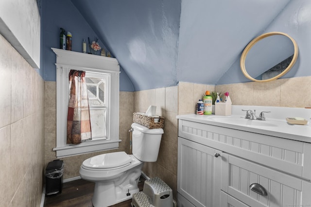 bathroom featuring tile walls, vanity, wood-type flooring, vaulted ceiling, and toilet