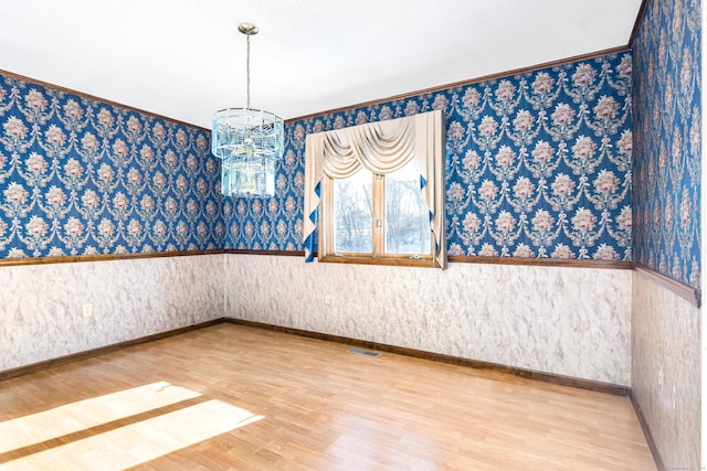 unfurnished room featuring hardwood / wood-style flooring and a chandelier