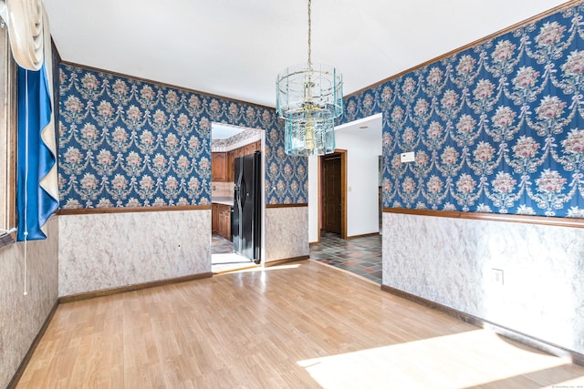 spare room featuring crown molding, a chandelier, and light hardwood / wood-style floors