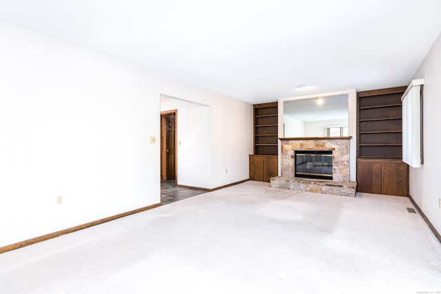 unfurnished living room with carpet flooring, built in features, and a fireplace