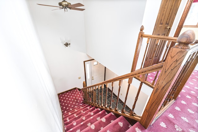 staircase with ceiling fan and carpet flooring