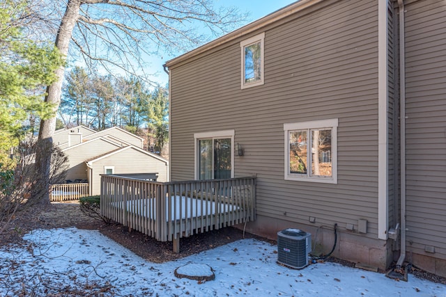 snow covered rear of property featuring cooling unit and a wooden deck