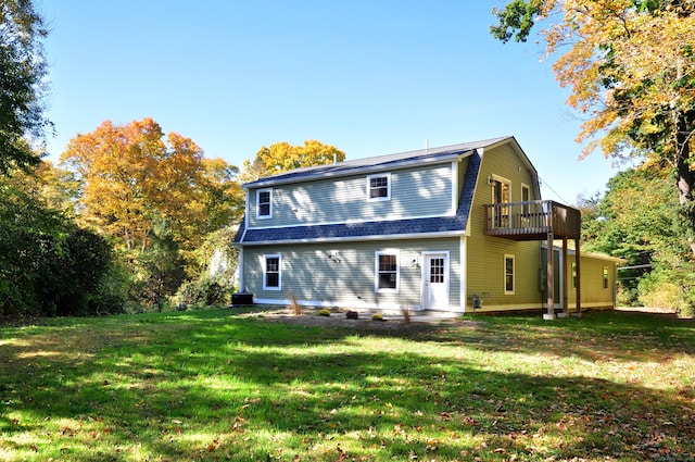 rear view of house featuring central AC unit and a lawn