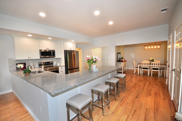 kitchen with stainless steel appliances, sink, a breakfast bar area, and white cabinets