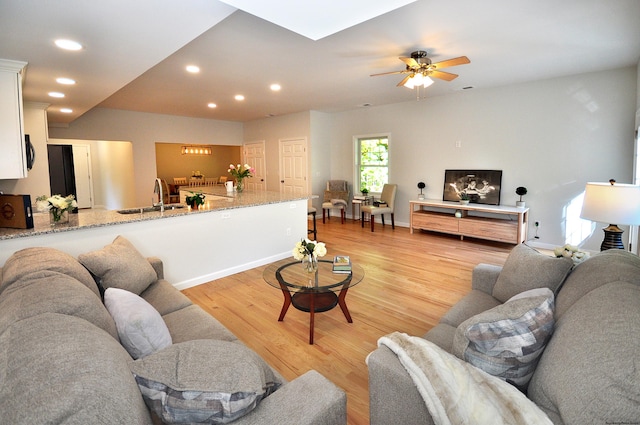 living room with sink, light hardwood / wood-style flooring, a skylight, and ceiling fan