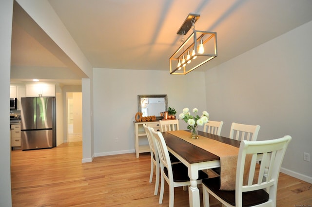 dining space featuring light hardwood / wood-style flooring and a notable chandelier