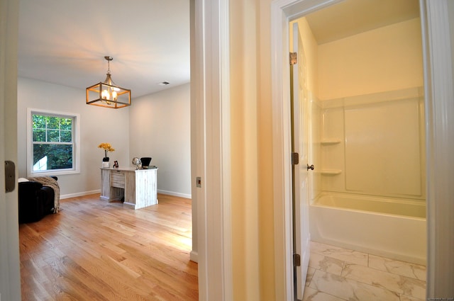 corridor with a notable chandelier and light wood-type flooring