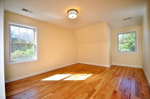 additional living space featuring vaulted ceiling and light hardwood / wood-style floors