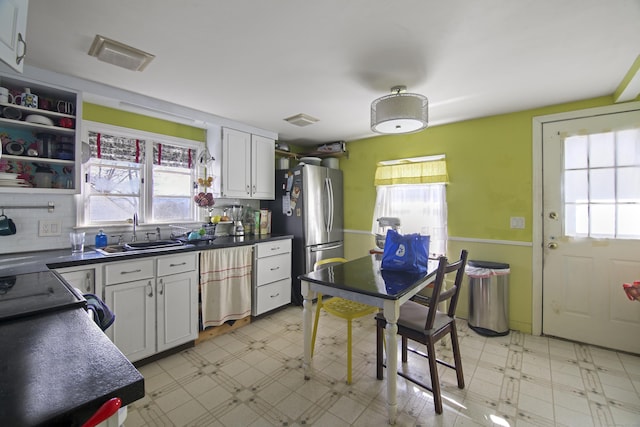 kitchen with white cabinetry, sink, stainless steel fridge, and plenty of natural light