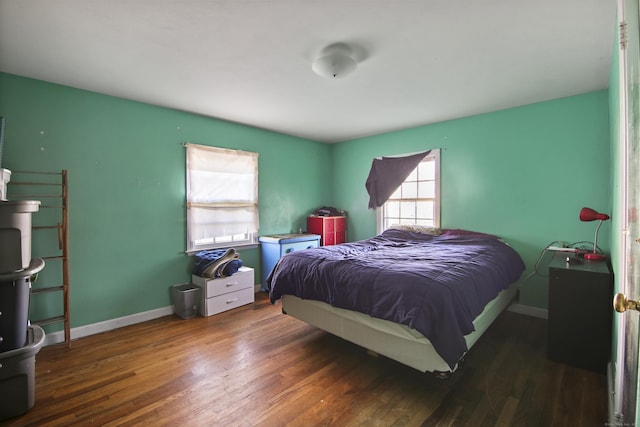 bedroom with multiple windows and dark hardwood / wood-style floors