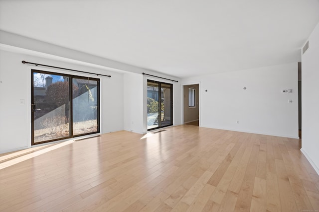 unfurnished room with a healthy amount of sunlight and light hardwood / wood-style floors