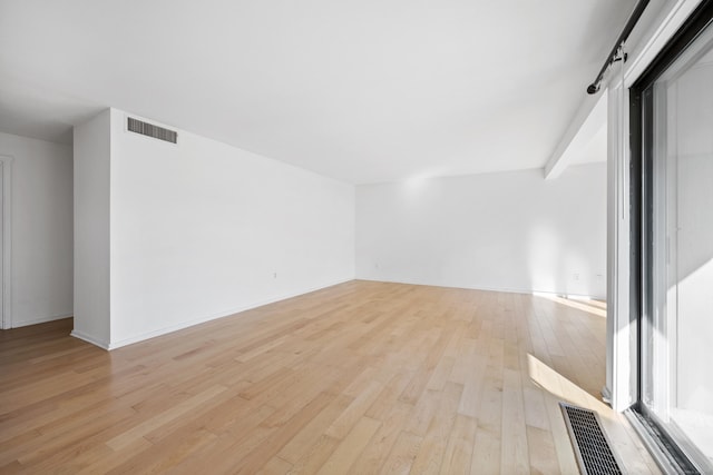 unfurnished room with beam ceiling and light wood-type flooring