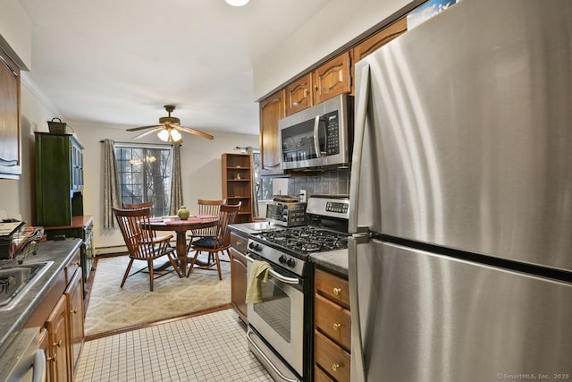 kitchen featuring crown molding, ceiling fan, appliances with stainless steel finishes, backsplash, and a baseboard radiator