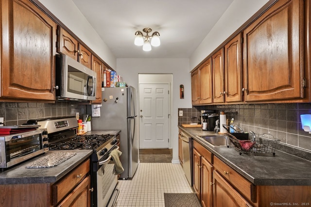 kitchen featuring sink, appliances with stainless steel finishes, an inviting chandelier, backsplash, and light tile patterned flooring