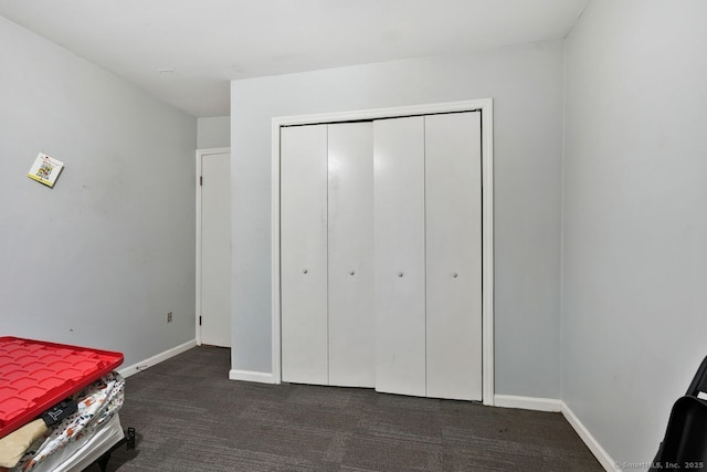 unfurnished bedroom featuring dark carpet and a closet