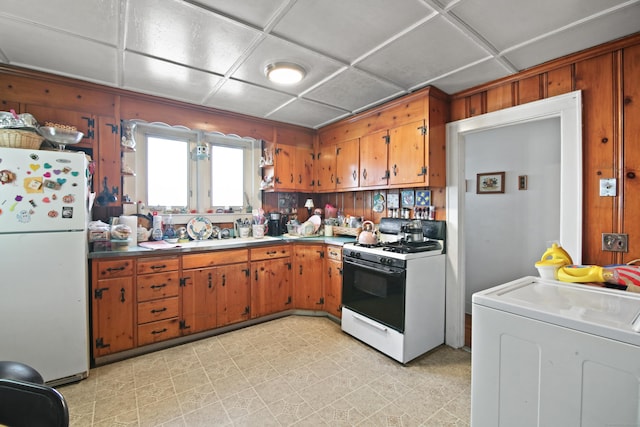 kitchen with wooden walls, white appliances, washer / clothes dryer, and a drop ceiling