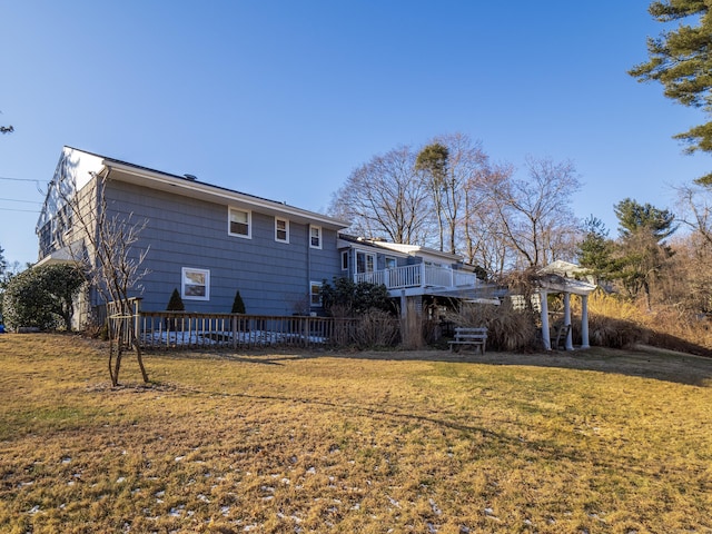 rear view of house featuring a wooden deck and a lawn