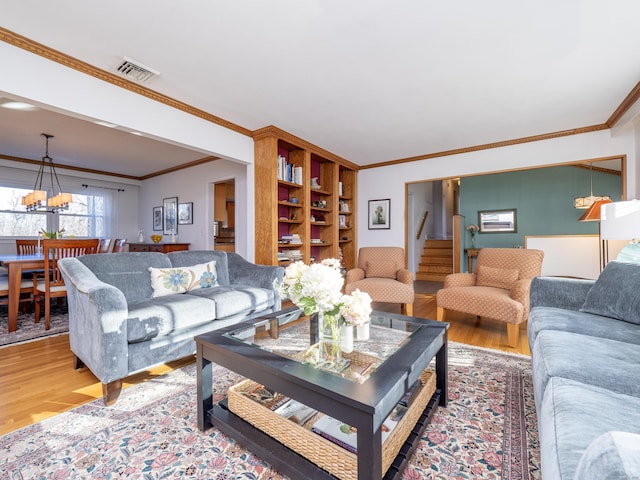 living room featuring an inviting chandelier, ornamental molding, and hardwood / wood-style floors