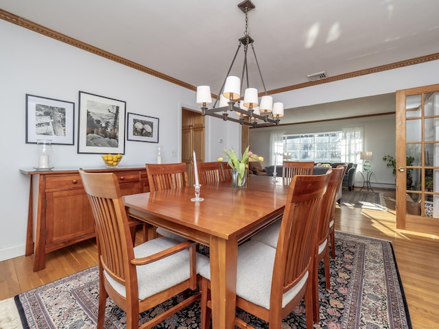 dining space featuring ornamental molding, a chandelier, and light hardwood / wood-style floors