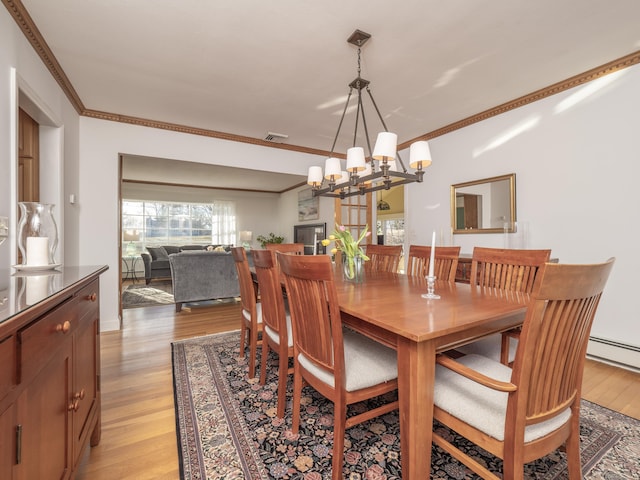 dining space with a notable chandelier, crown molding, light hardwood / wood-style flooring, and a baseboard radiator