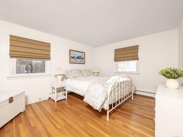 bedroom with hardwood / wood-style flooring and a baseboard heating unit