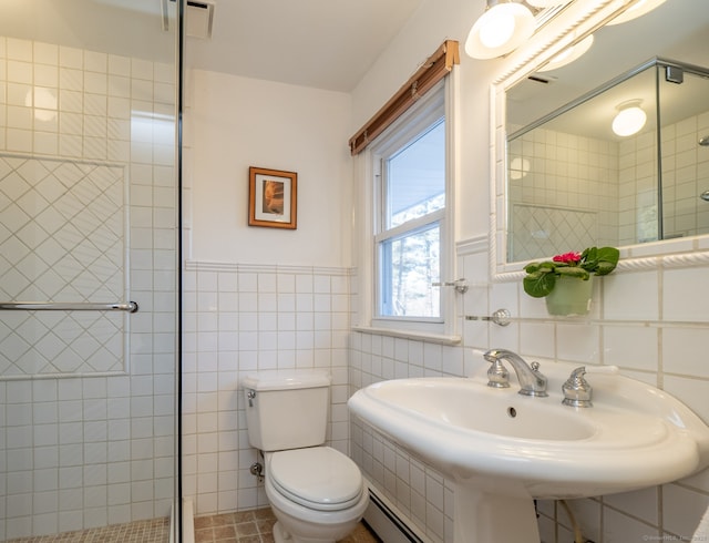 bathroom featuring a shower with shower door, a baseboard radiator, sink, tile walls, and toilet