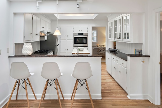 kitchen featuring white cabinetry, hanging light fixtures, kitchen peninsula, and a kitchen bar