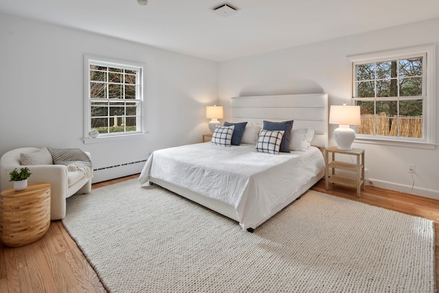 bedroom featuring hardwood / wood-style flooring and baseboard heating