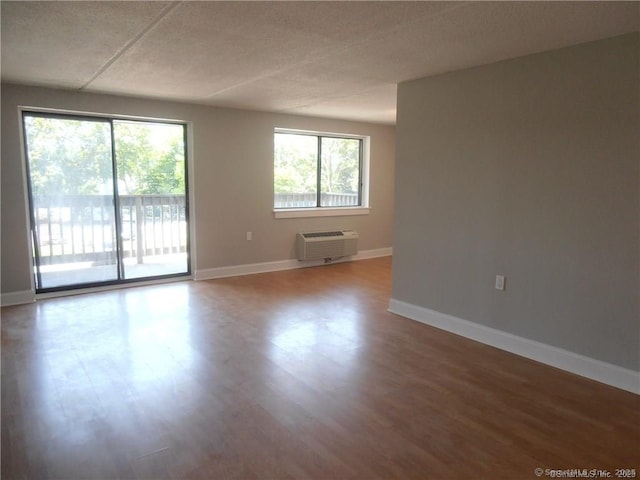 empty room with hardwood / wood-style flooring, a wall mounted air conditioner, and a textured ceiling