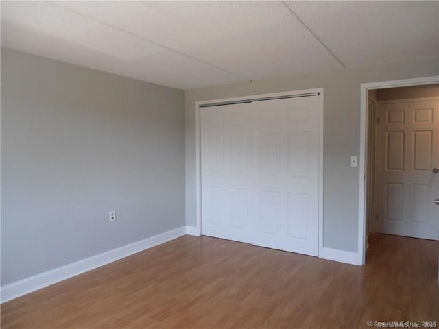 unfurnished bedroom with wood-type flooring and a closet