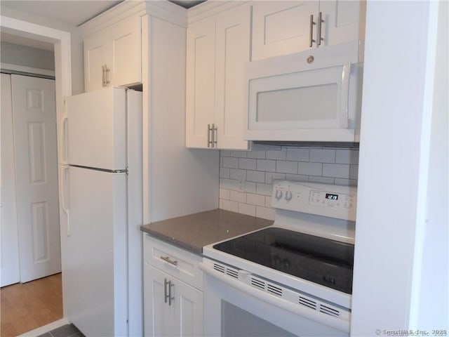 kitchen with tasteful backsplash, white appliances, and white cabinets