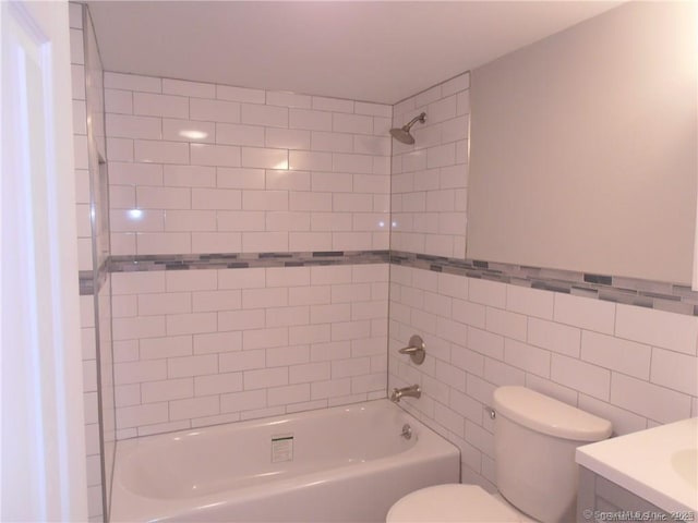 full bathroom featuring tiled shower / bath combo, vanity, and toilet