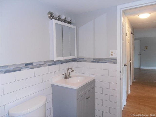 bathroom with hardwood / wood-style flooring, vanity, toilet, and tile walls