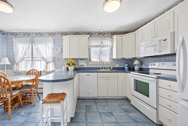 kitchen featuring tasteful backsplash, white cabinetry, sink, white appliances, and a textured ceiling