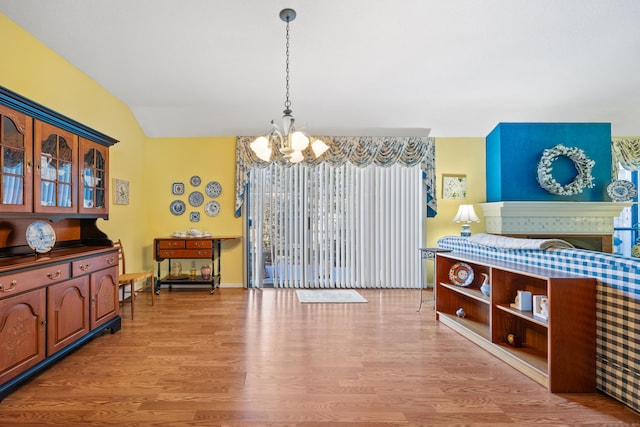 dining area featuring an inviting chandelier, vaulted ceiling, and light wood-type flooring