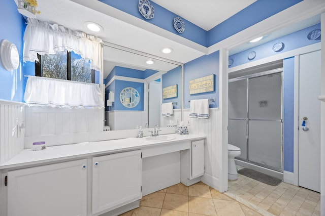 bathroom featuring vanity, toilet, tile patterned flooring, and a shower with door