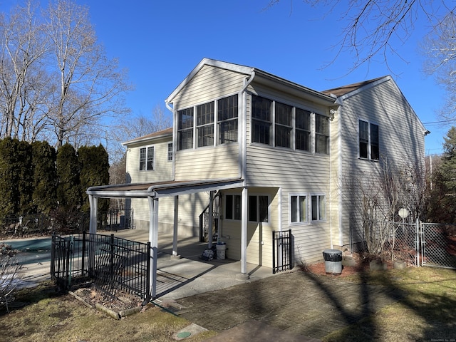 back of property featuring a patio area, a fenced in pool, a sunroom, and fence