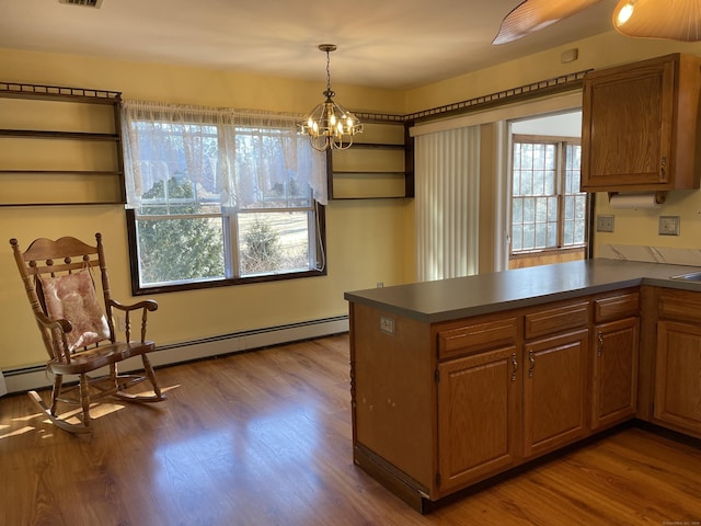 kitchen with brown cabinetry, a peninsula, dark countertops, and dark wood-style flooring