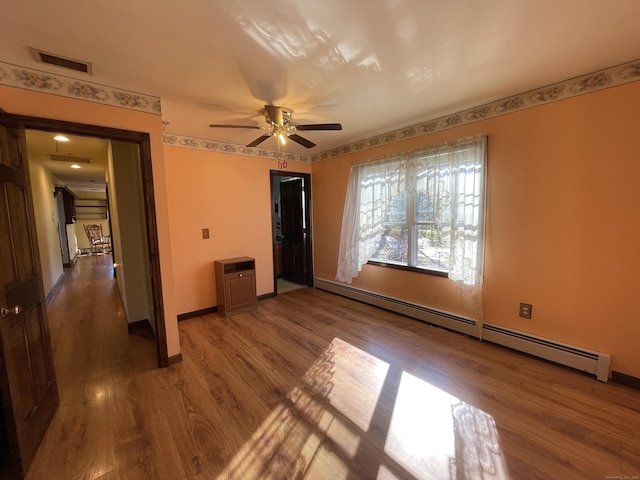 unfurnished bedroom featuring baseboards, wood finished floors, visible vents, and a baseboard radiator