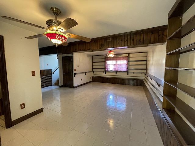 empty room featuring beamed ceiling, light tile patterned floors, a ceiling fan, and baseboards