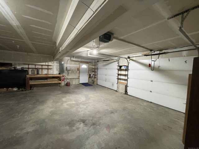 garage with electric panel, a garage door opener, and heating fuel