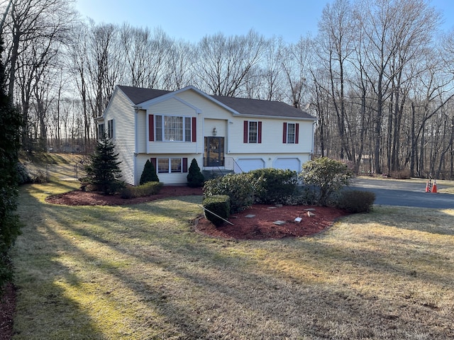 raised ranch featuring a garage and a front lawn