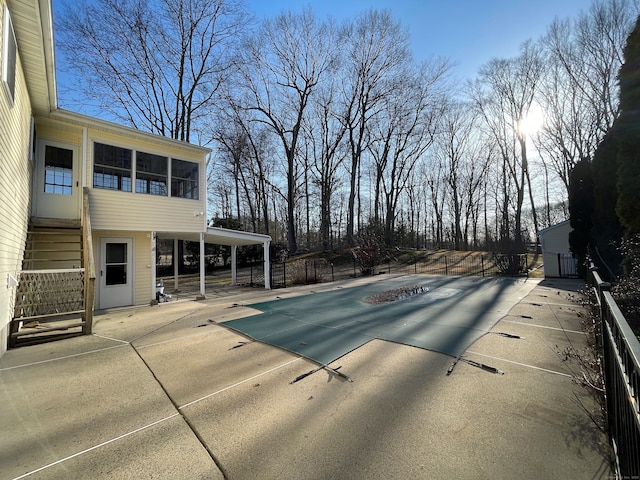 view of swimming pool featuring a patio, fence, and a sunroom