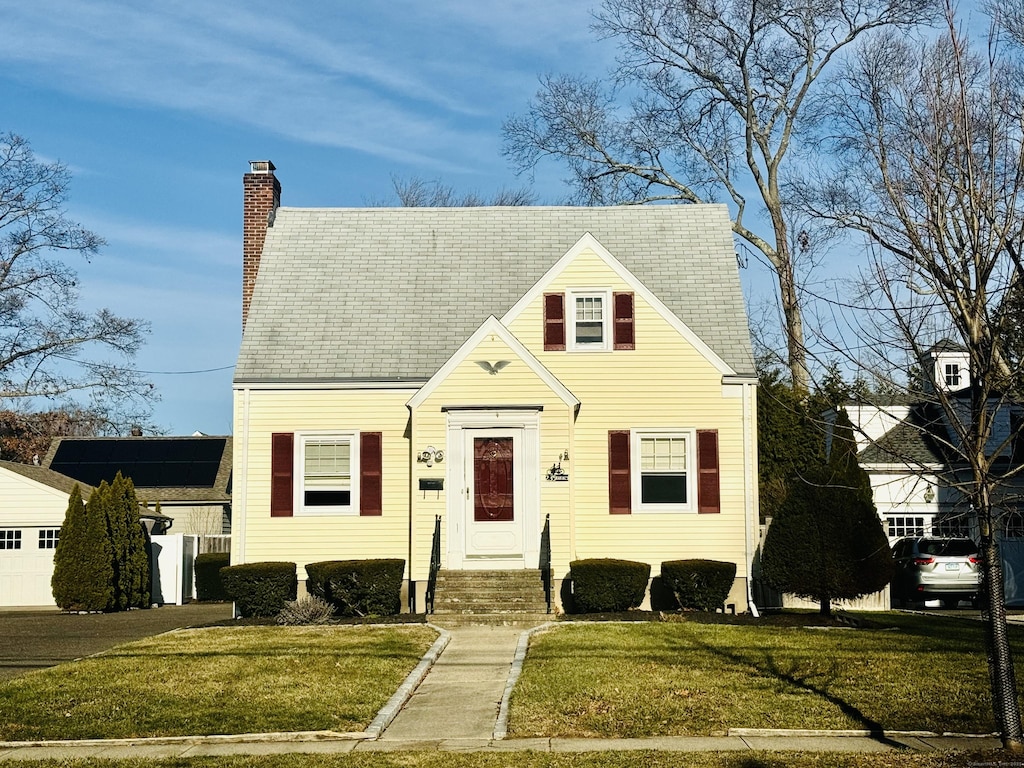 cape cod house featuring a front yard