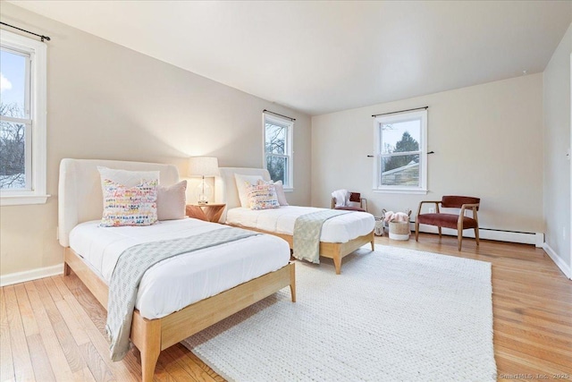 bedroom with baseboard heating and light hardwood / wood-style flooring