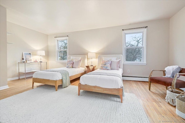 bedroom with a baseboard radiator and light hardwood / wood-style floors