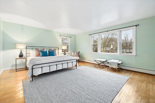 bedroom featuring a baseboard heating unit and light hardwood / wood-style flooring